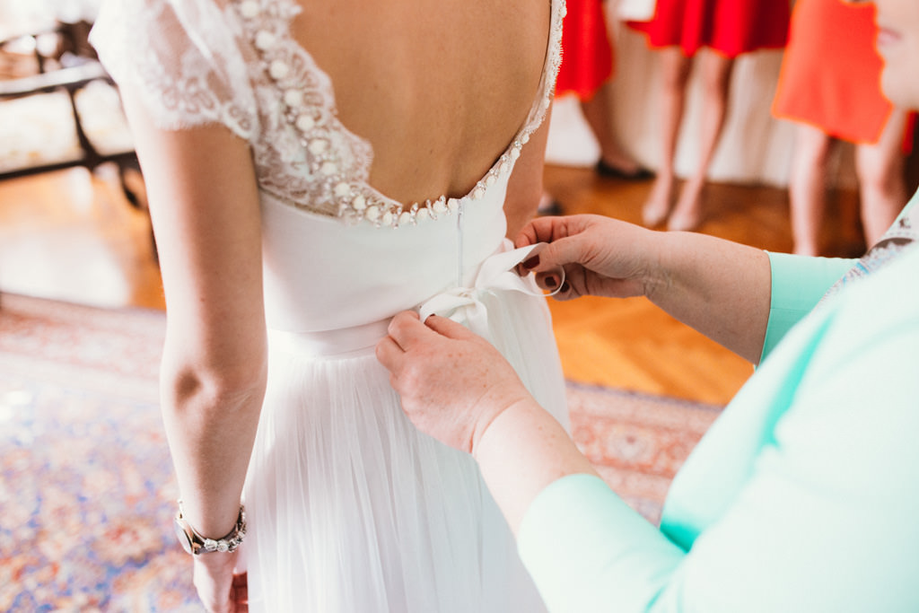 mother helping bride to get dressed
