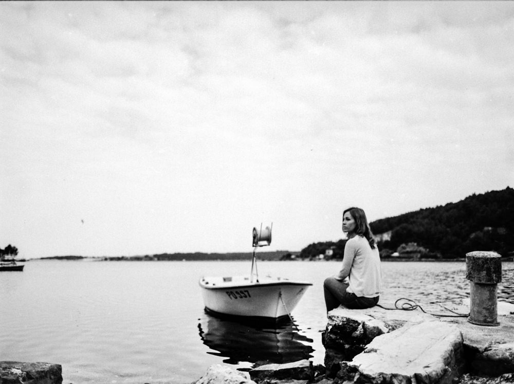 bride sitting by the sea in front of a boat