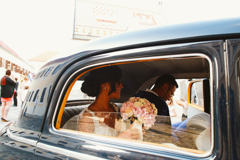 groom and bride in front of church in an oldtimer